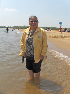 2 photos show Nanta standing in the water with her pants rolled up to her knees.  The water is making little waves, and is covering her ankles.